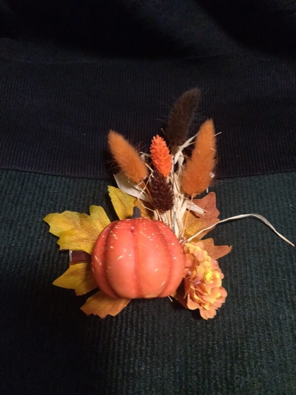 Pumpkin on a yellow fall leaf with wheat stalks