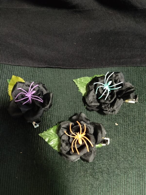 Black rose on green leaf with a tuquoise/orange/purple spider